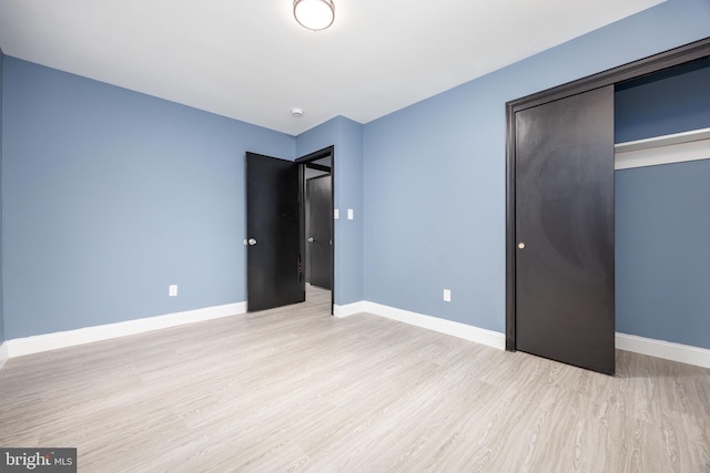 unfurnished bedroom with light wood-type flooring and a closet