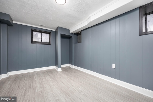 basement featuring wood-type flooring and a textured ceiling