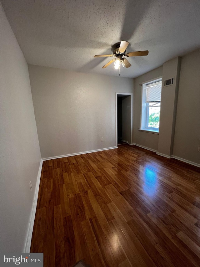 spare room featuring ceiling fan, a textured ceiling, and dark hardwood / wood-style flooring