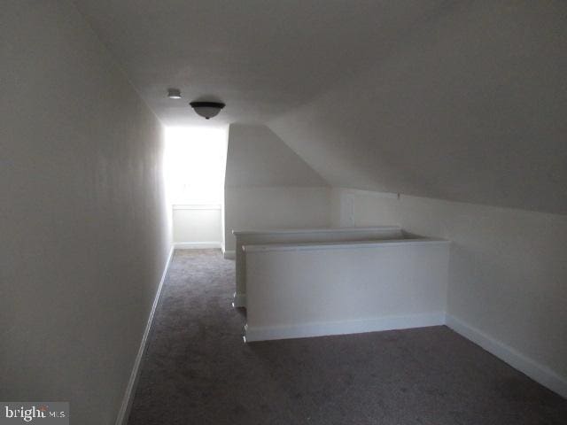 bonus room featuring lofted ceiling and dark colored carpet