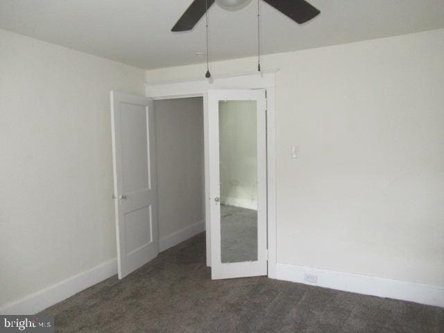 unfurnished room featuring ceiling fan and dark colored carpet