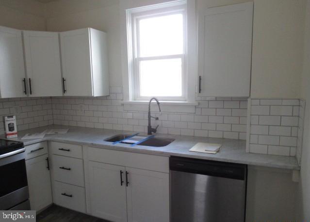 kitchen with white cabinetry, sink, backsplash, and stainless steel appliances