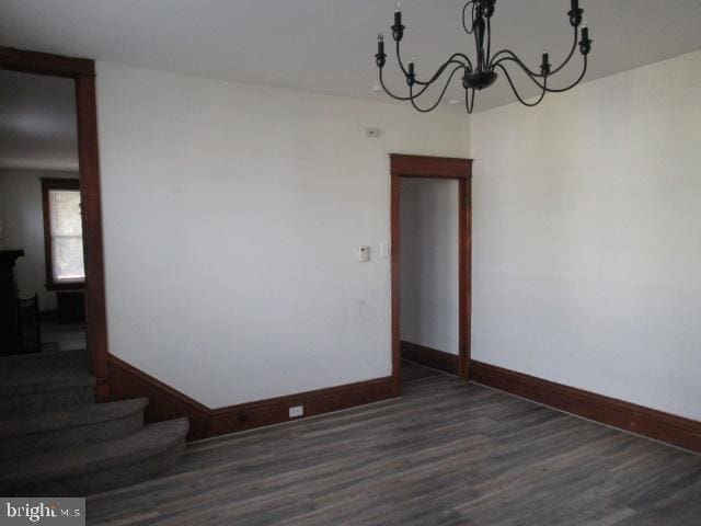 unfurnished room featuring a chandelier and dark hardwood / wood-style flooring