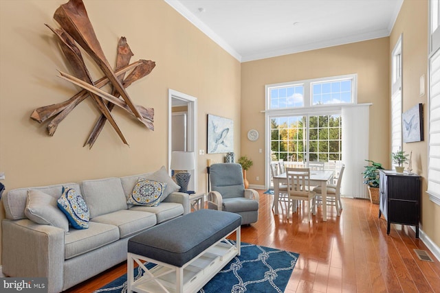 living room featuring hardwood / wood-style flooring, ornamental molding, and a healthy amount of sunlight