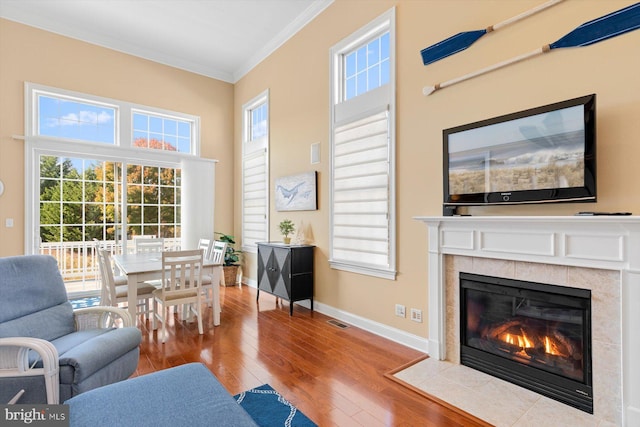 sitting room with crown molding, a tiled fireplace, and light hardwood / wood-style floors