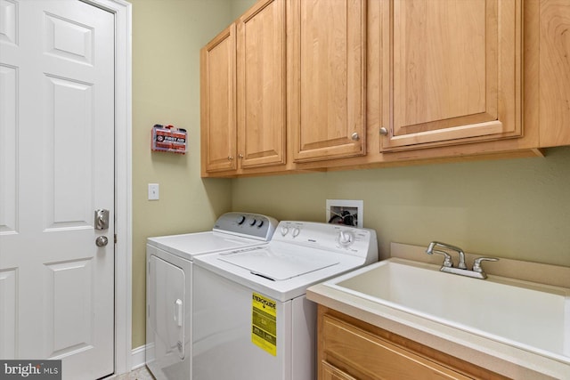 clothes washing area featuring cabinets, sink, and washer and dryer