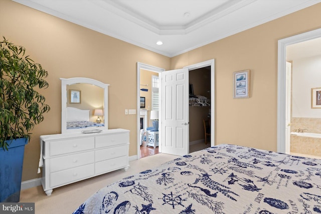 bedroom with ornamental molding, light carpet, ensuite bath, and a tray ceiling