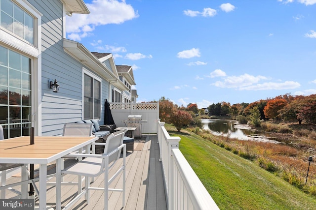 wooden deck with grilling area, a lawn, and a water view