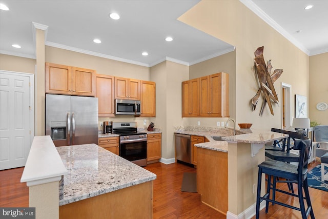 kitchen featuring ornamental molding, appliances with stainless steel finishes, a kitchen breakfast bar, kitchen peninsula, and light stone countertops