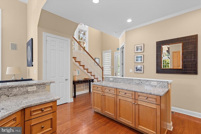 kitchen featuring crown molding, light stone countertops, and hardwood / wood-style flooring