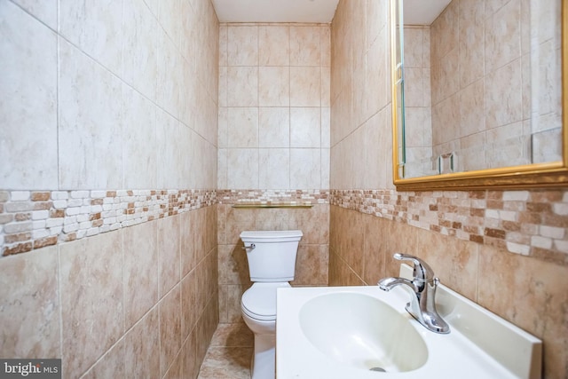 bathroom featuring sink, tile walls, and toilet