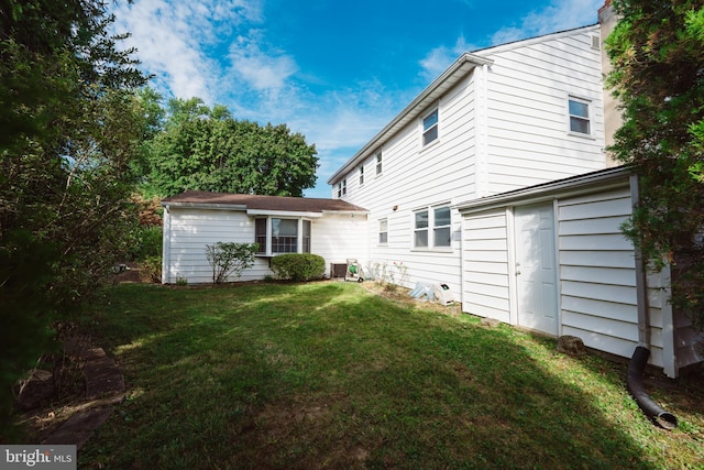 back of house with central AC unit and a lawn