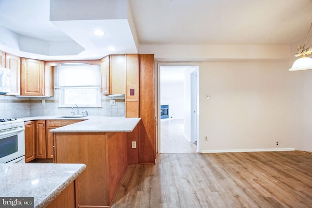 kitchen featuring sink, white appliances, tasteful backsplash, light stone counters, and light hardwood / wood-style floors