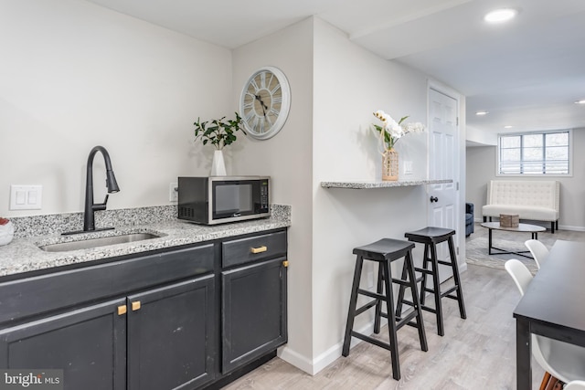 kitchen with light stone counters, sink, and light hardwood / wood-style flooring