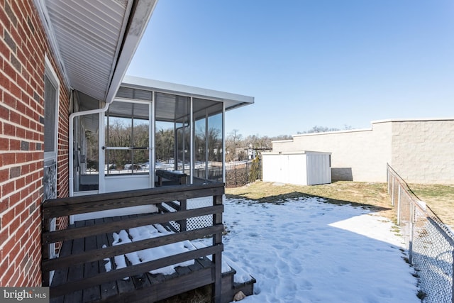 yard covered in snow with a sunroom and a shed