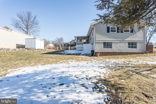 snow covered property featuring a sunroom and a yard