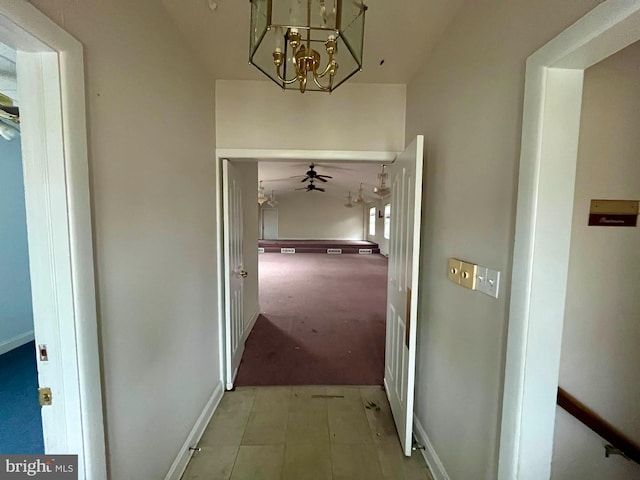 hallway featuring light carpet and a notable chandelier