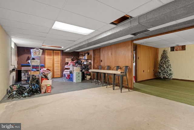 basement with a paneled ceiling and wood walls