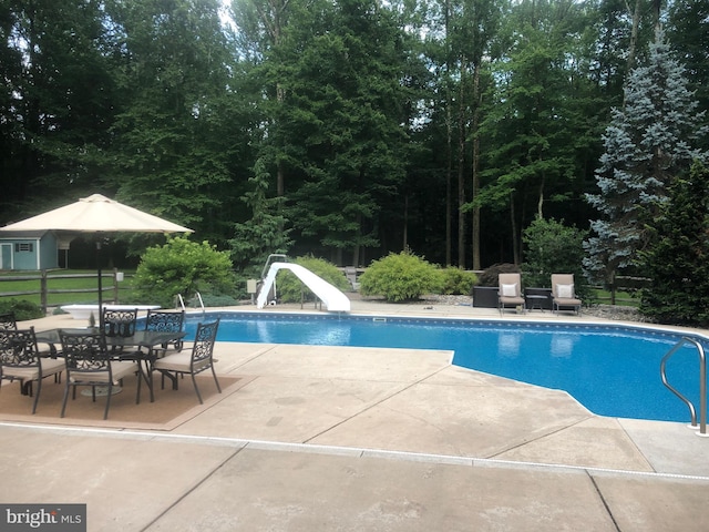 view of swimming pool featuring a water slide and a patio