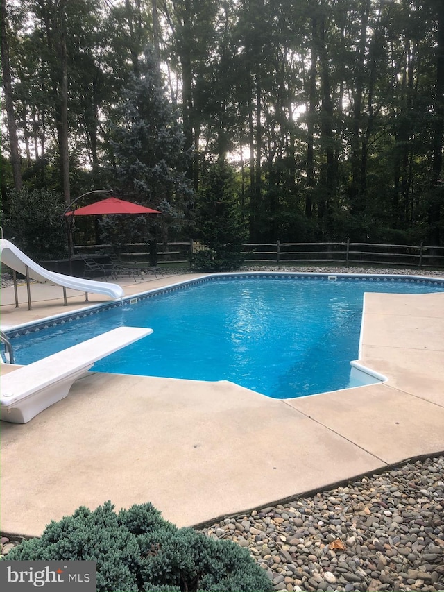 view of pool with a diving board, a water slide, and a patio area