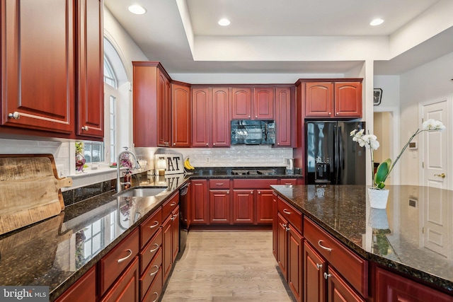 kitchen featuring sink, decorative backsplash, dark stone counters, and black appliances