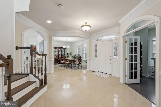 tiled entrance foyer with crown molding and a chandelier