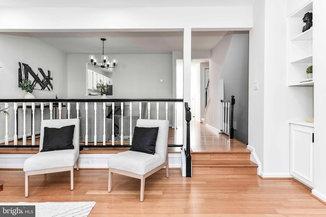 sitting room featuring an inviting chandelier, light wood-type flooring, and built in shelves