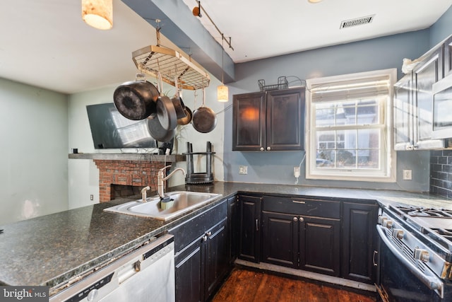 kitchen with a fireplace, dishwasher, sink, kitchen peninsula, and stainless steel range with gas stovetop