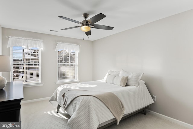 bedroom featuring ceiling fan, light colored carpet, and multiple windows