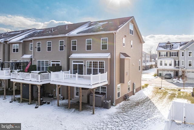 snow covered rear of property with a wooden deck and central AC