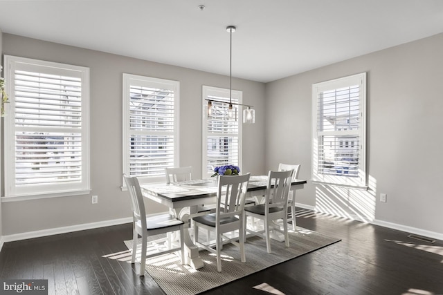 dining area with dark wood-type flooring and a notable chandelier