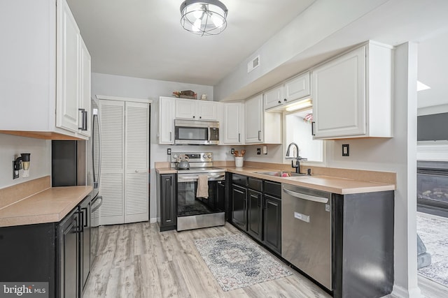 kitchen with sink, stainless steel appliances, light hardwood / wood-style floors, and white cabinets