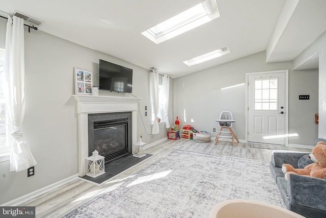 recreation room with wood-type flooring and vaulted ceiling with skylight