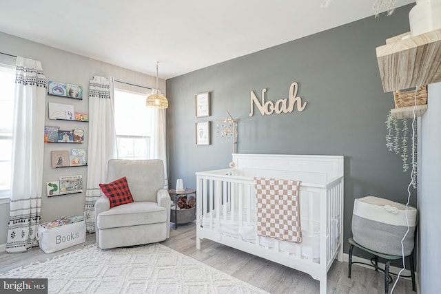 bedroom with hardwood / wood-style flooring and a nursery area