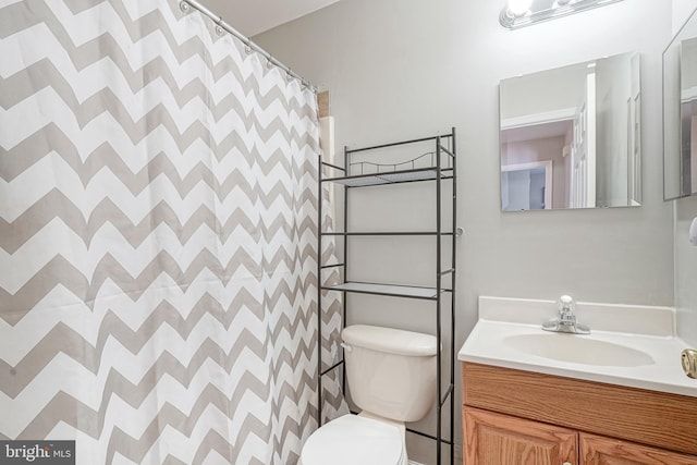 bathroom with walk in shower, vanity, and toilet