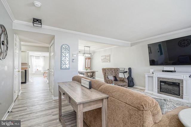 living room with ornamental molding, a stone fireplace, and light wood-type flooring