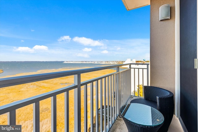 balcony with a water view and a view of the beach