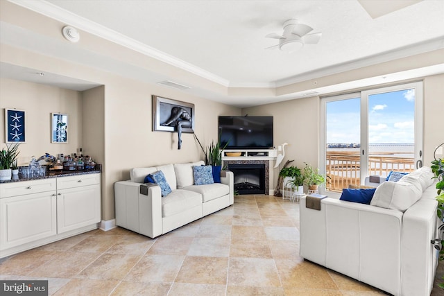 living room with ornamental molding, ceiling fan, and a raised ceiling