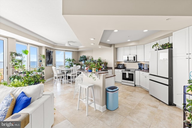 kitchen featuring appliances with stainless steel finishes, light tile patterned floors, a center island, white cabinetry, and a kitchen breakfast bar