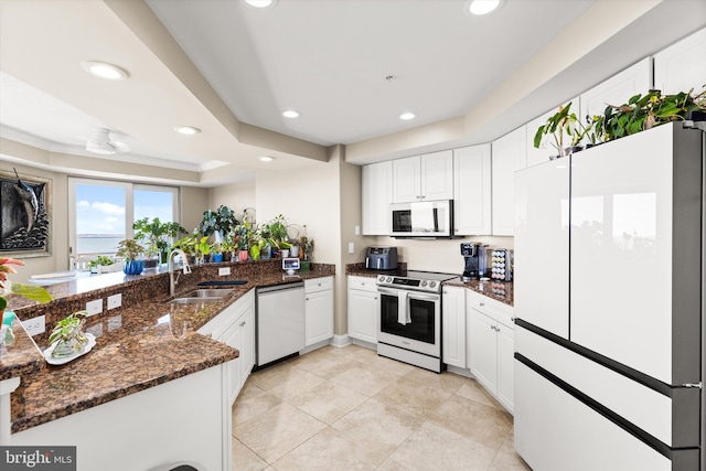 kitchen featuring appliances with stainless steel finishes, sink, white cabinetry, and dark stone counters