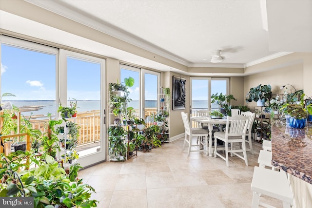 sunroom / solarium featuring ceiling fan, a water view, and a raised ceiling