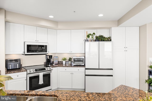 kitchen with white cabinets, stainless steel range with electric stovetop, and dark stone counters