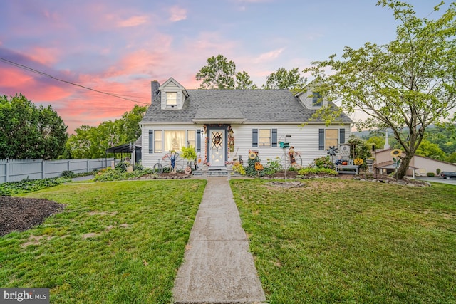 cape cod-style house featuring a lawn and a carport