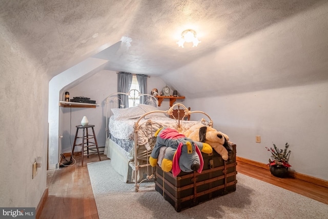 bedroom featuring a textured ceiling, lofted ceiling, and wood-type flooring