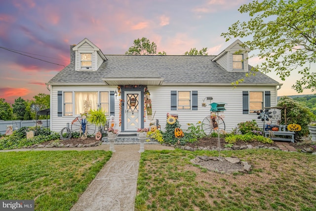 cape cod home featuring a lawn