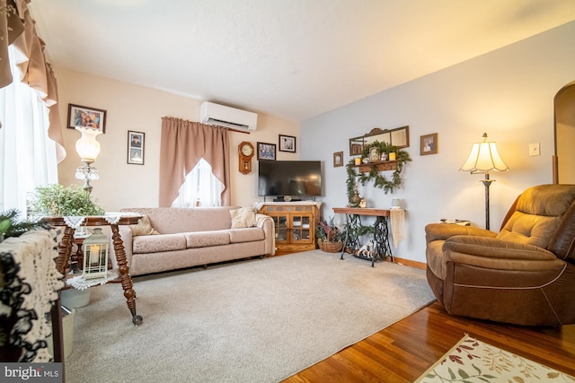 living room with a healthy amount of sunlight, hardwood / wood-style flooring, and a wall unit AC