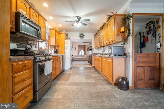 kitchen with appliances with stainless steel finishes, ceiling fan, a wall unit AC, and sink