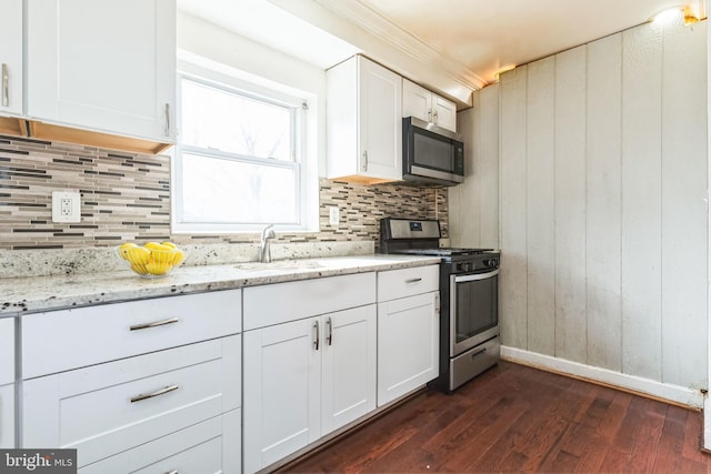 kitchen featuring appliances with stainless steel finishes, dark hardwood / wood-style floors, white cabinets, and light stone counters