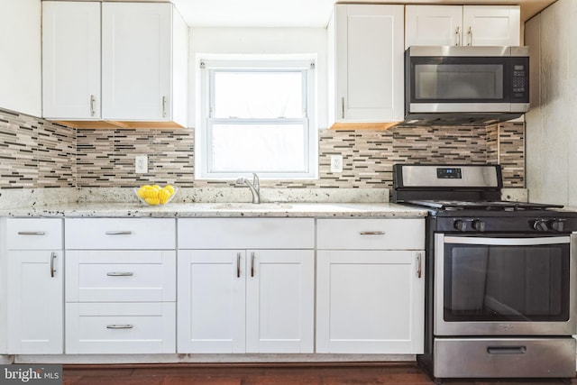 kitchen featuring sink, stainless steel appliances, white cabinets, and light stone countertops