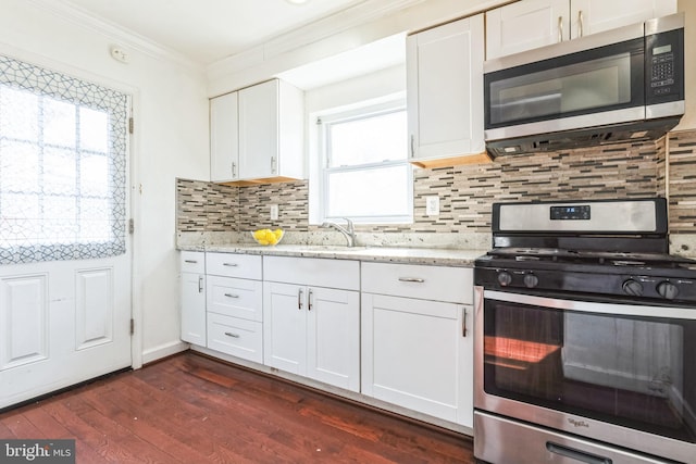 kitchen featuring crown molding, dark wood-type flooring, stainless steel appliances, light stone counters, and white cabinets